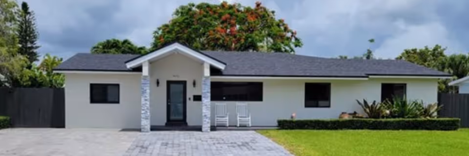 Single-story light-colored facility exterior with a front entrance and two rocking chairs.