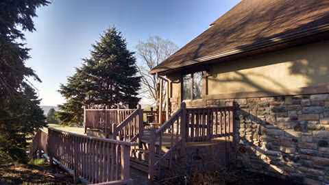 Exterior view of Pond View Manor with a wooden deck and surrounding trees.