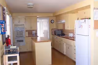 Cozy cream-colored kitchen with cabinets, appliances, and a central island in Sunshine Home Care Ii.