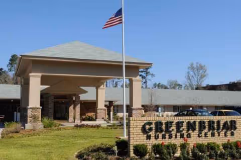 Front view of Greenbriar Community Care Center entrance with flagpole and landscaping.