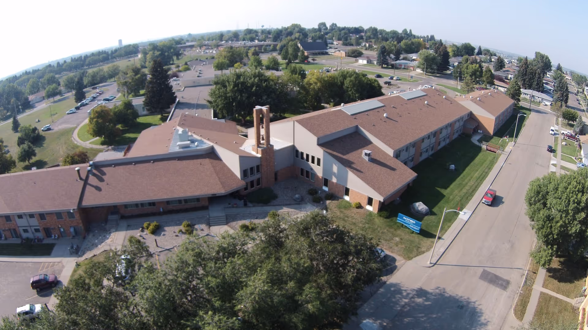 Aerial view of Good Samaritan Society – Marillac Manor, a large low-rise senior living building with brown roofs, lawns, trees, and surrounding streets.