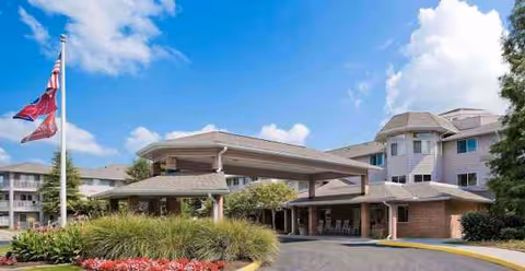 Exterior view of Holiday Echo Ridge entrance with covered drive, flagpole, and landscaping.