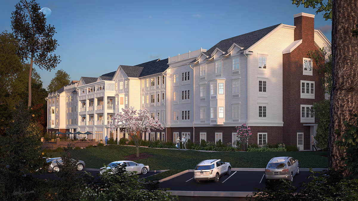 Exterior view of a multi-story senior living facility building with white siding and brick accents, surrounded by trees and landscaping. Several cars are parked in the parking lot in front of the building, and a few people are walking near the entrance. The sky is clear with a visible moon.
