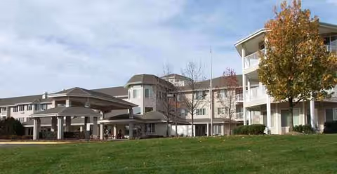 Exterior view of Holiday Redbud Hills senior living facility with lawn and trees.