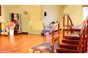 Interior common area with hardwood floors, a small carpeted staircase with wooden handrails, a stool and seating against pale yellow walls.