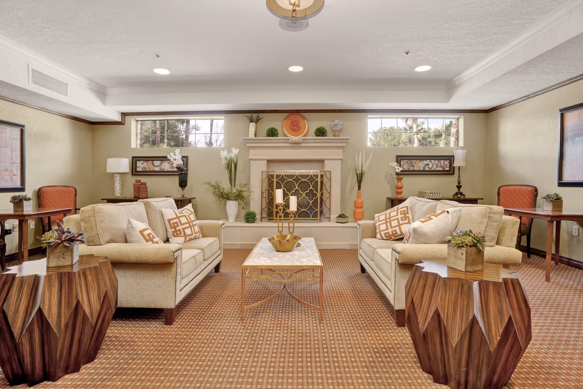 A furnished communal living room with two sofas facing a central fireplace, a coffee table, and decorative accents.