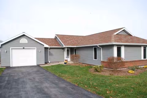 Exterior view of Bluefield Manor, a single-story gray senior living facility with driveway and garage.