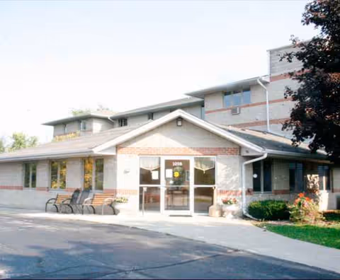 Exterior view of Kettle Moraine Gardens entrance with glass doors and benches.