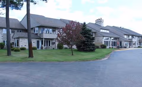 Exterior view of River Run Assisted Living complex with manicured lawn and trees.