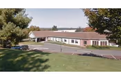 Exterior view of a single-story senior care facility with a parking lot.
