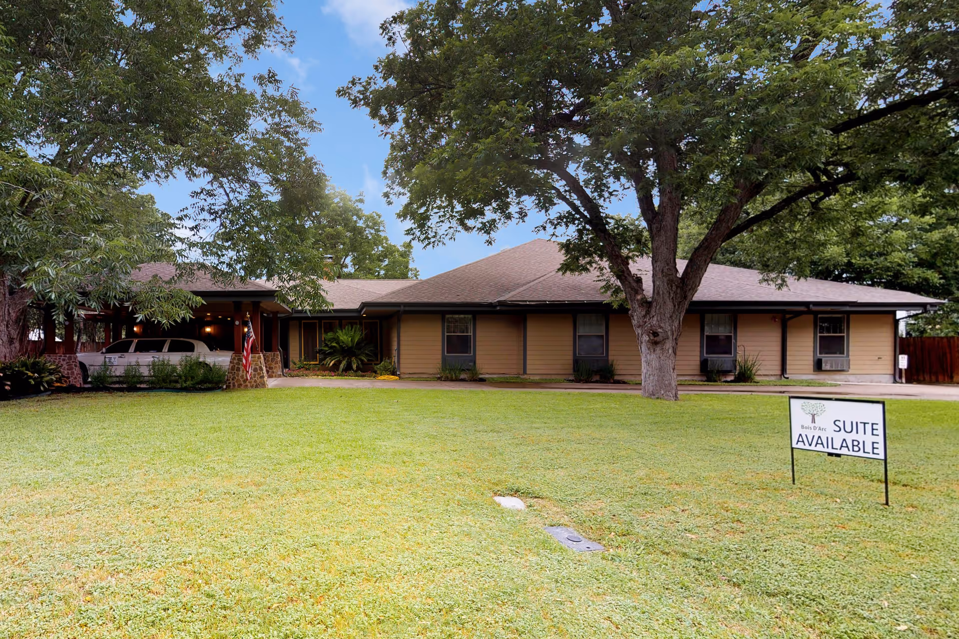 A single-story assisted living building with a large front lawn and a 'Suite Available' sign.