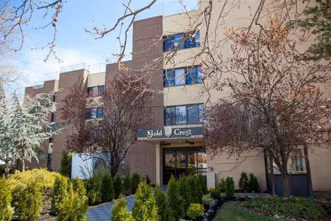 Exterior view of Gold Crest Care Center with brick facade and landscaped shrubs.