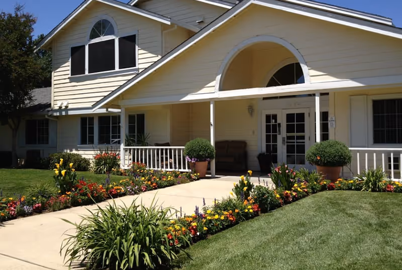 Exterior view of Oakwood Meadows Assisted Living entrance with flower beds.
