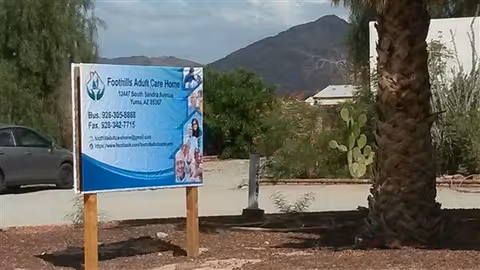 Outdoor view of Foothills Adult Care Home sign amid desert landscaping