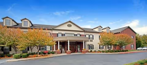 Exterior view of The Carriages of Rivergate, a senior living facility with a grand entrance.