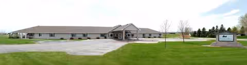 A single-story senior living facility with entrance canopy, parking lot, and manicured lawn.