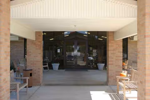 Entrance to Parkview Manor Nursing & Rehabilitation with brick columns, glass doors, and outdoor seating.