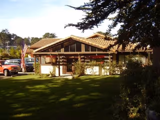 The Chalet Montara's single-story chalet-style building with lawn, flag, and parked car in front.