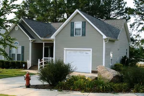 Front view of a gray residential house with attached garage, driveway, and landscaping.