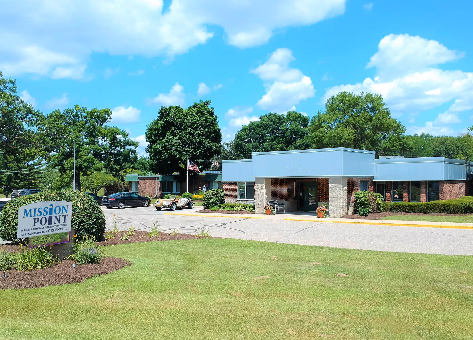 Front exterior of a single-story senior care building with entrance canopy, lawn and a Mission Point sign near the driveway.