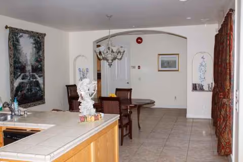 Open indoor dining area with kitchen island, chandelier, arched doorway, and chairs.