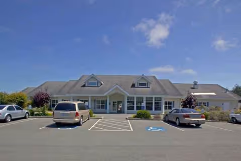 Single-story senior living building with a central entrance and surrounding parking lot.