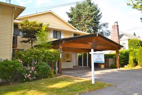 Exterior view of Tabor Hill Care Homes entrance with a wooden canopy and surrounding greenery.