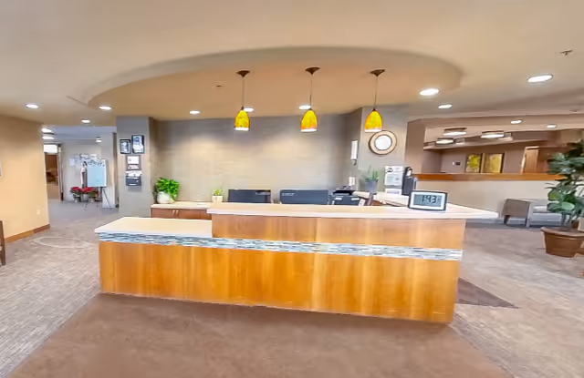 Reception desk and lobby area with a wooden front desk, three pendant lights, and seating in the background.