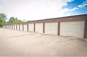 A row of closed garage doors in a long, single-story building under a partly cloudy sky.