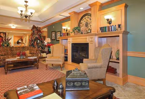 Cozy senior living lounge with fireplace, armchairs, sofa, and built-in bookshelves.