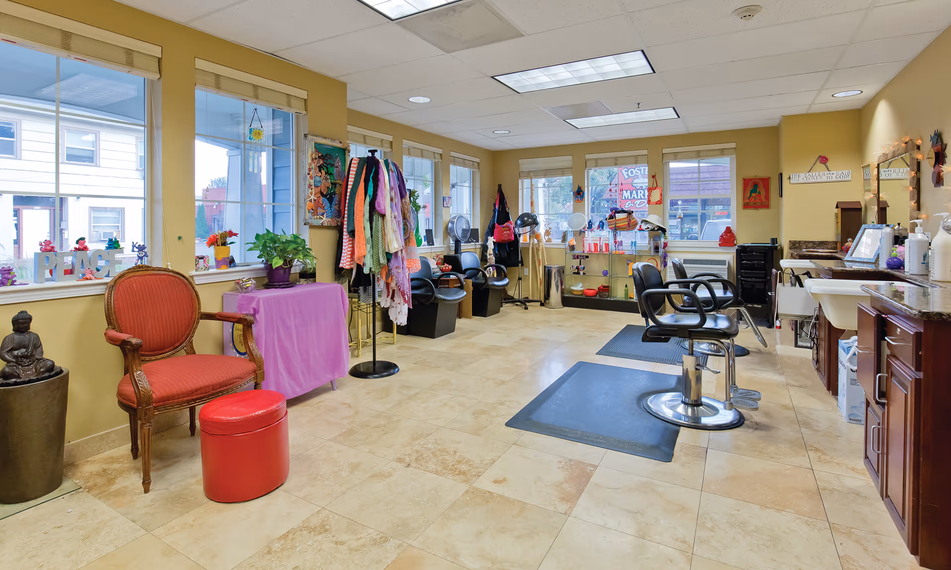 Bright hair salon inside a senior living facility with styling chairs, sinks, hairdryers, seating and colorful decorations.