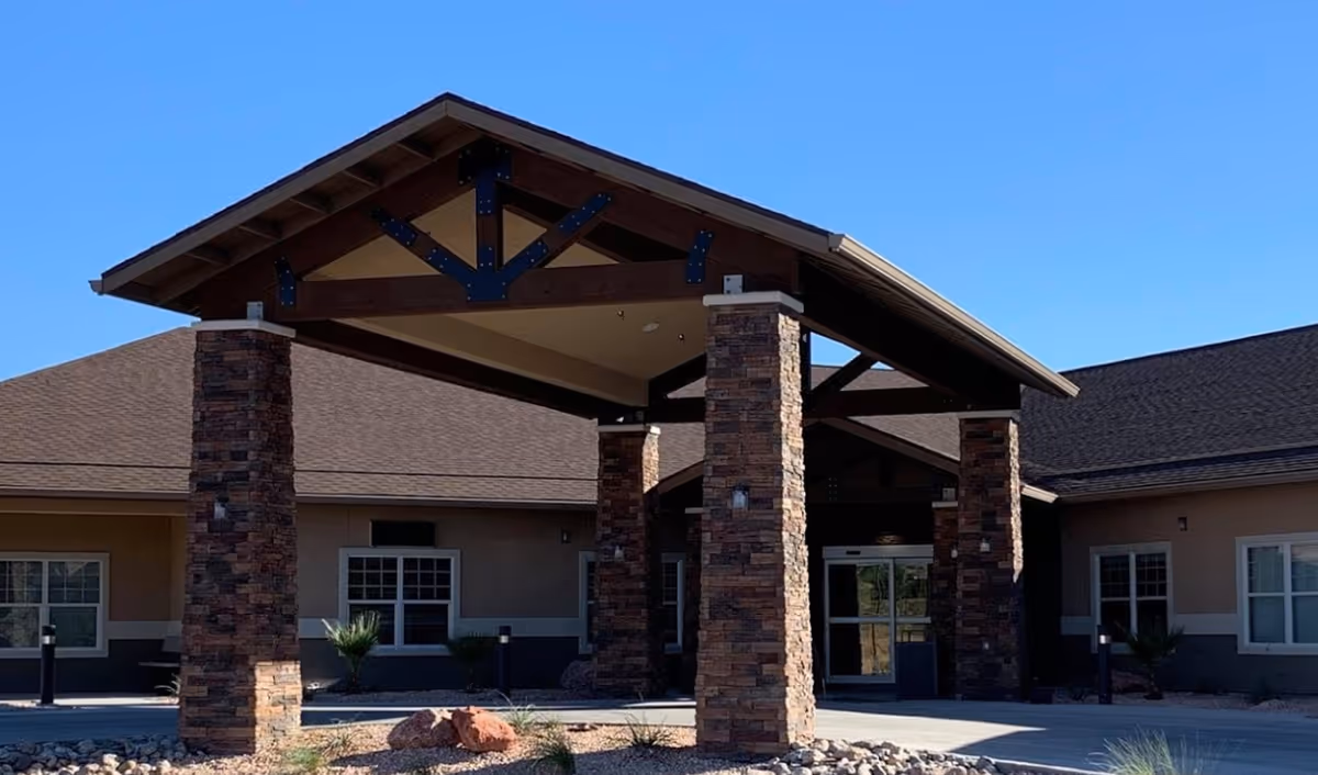 Exterior view of Mesa Valley Estates entrance with stone pillars and a covered porte-cochere.