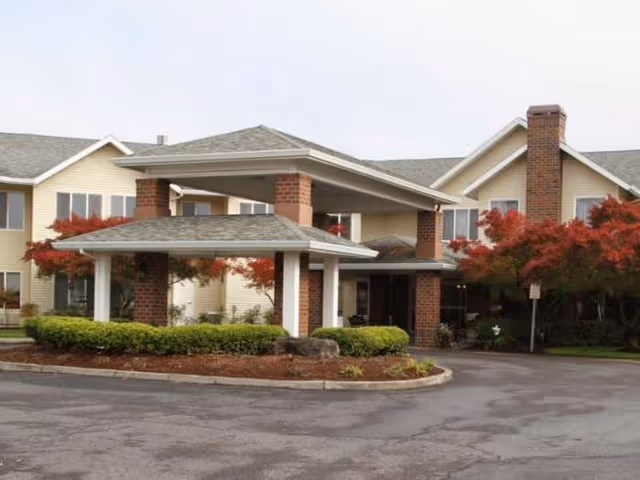 Exterior view of Jennings McCall senior living building with brick columns and landscaped entrance.