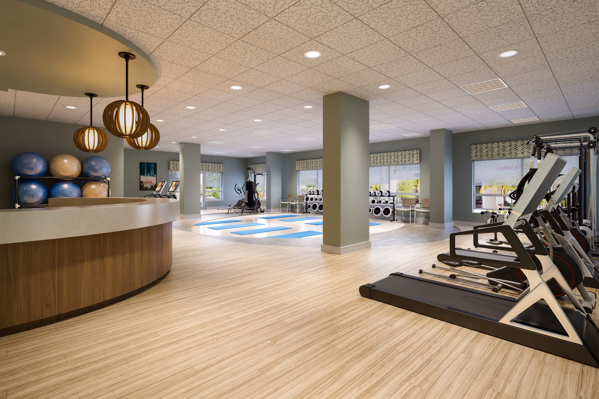Bright, modern fitness center with treadmills, weight racks, exercise balls and a reception desk.