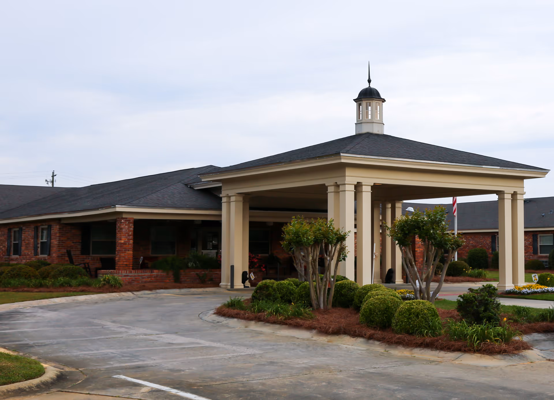 Front entrance with a covered portico and landscaping at a single-story brick health and rehabilitation facility.