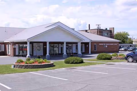Exterior view of a single-story facility with a covered front entrance and parking.