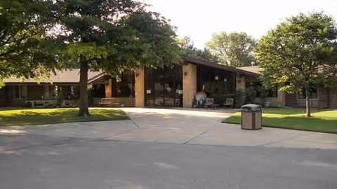 Villa Maria senior living facility entrance with trees, benches, and a wide driveway.