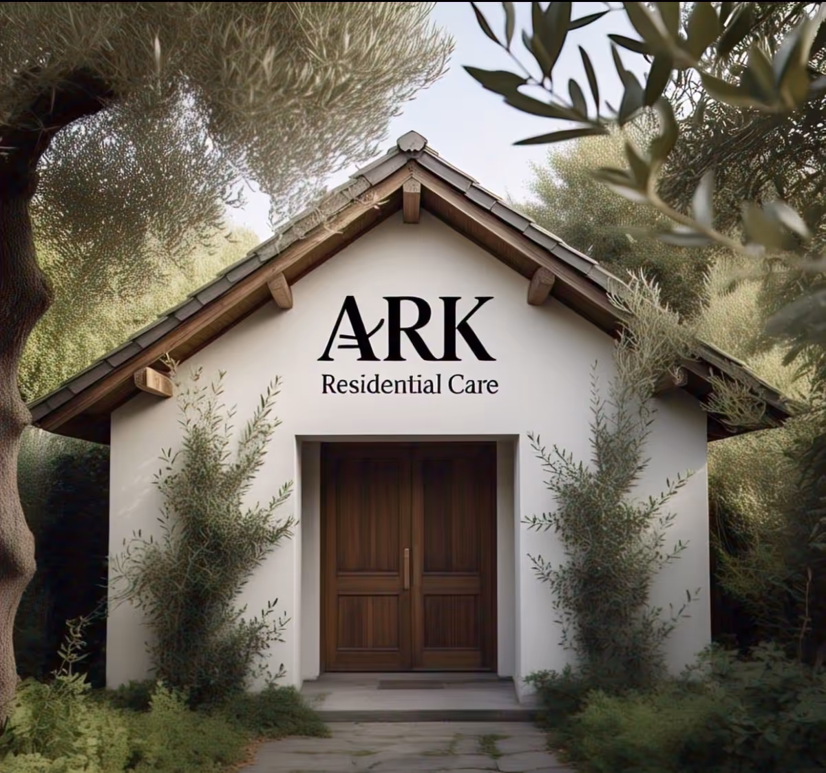 Front exterior view of a small building with a peaked roof, surrounded by trees and greenery. The building has a wooden double door and a sign above it that reads 'ARK Residential Care'.