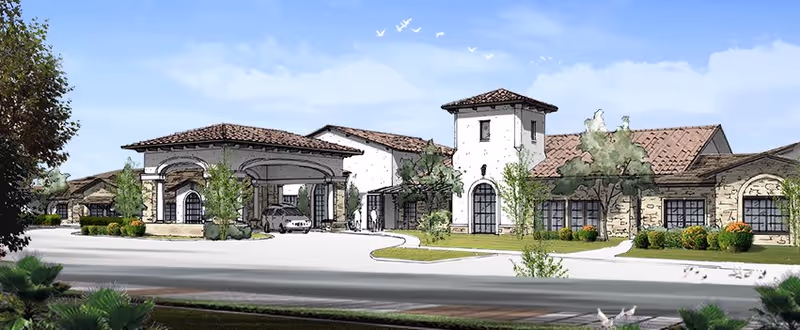 Exterior view of a senior living facility building with a Mediterranean architectural style, featuring a tiled roof, arched windows and doorways, a covered entrance with columns, and landscaped greenery around the building.