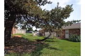 Grassy courtyard at Prairie Villa with a large tree and hammock between single-story brick buildings.