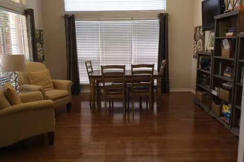 Cozy interior living area in a senior living facility with dining table and bookshelves.