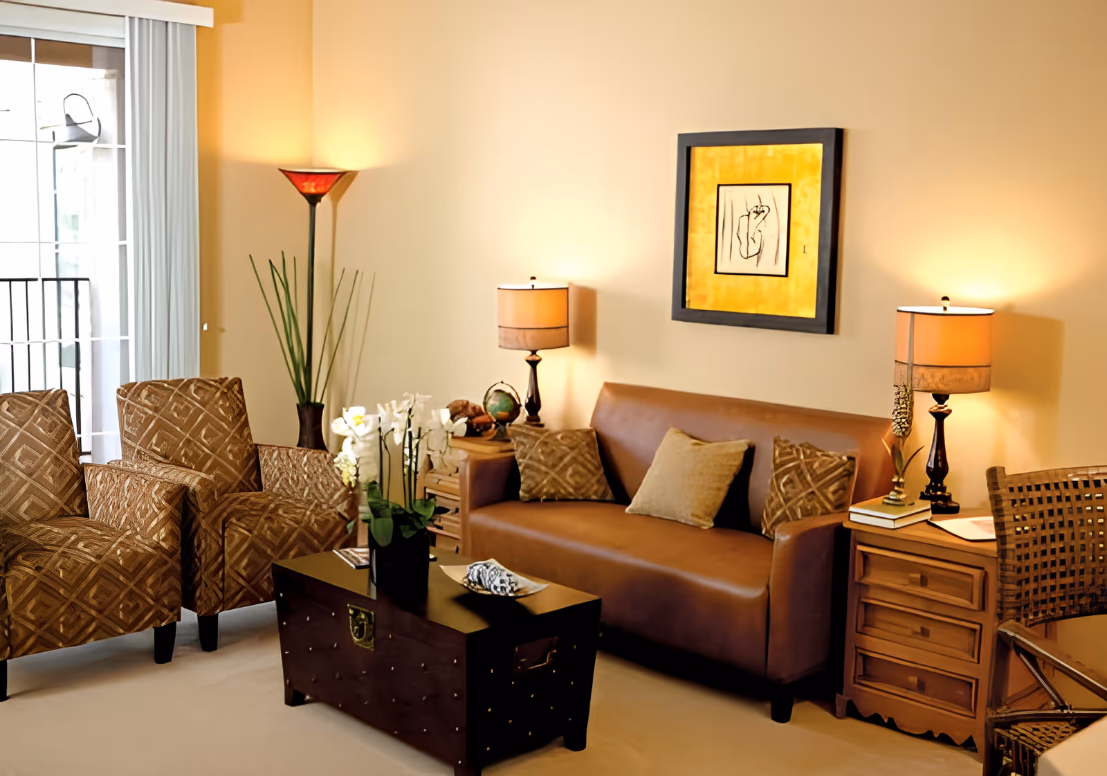 Sunlit living room with a leather sofa, patterned armchairs, coffee table and lamps.