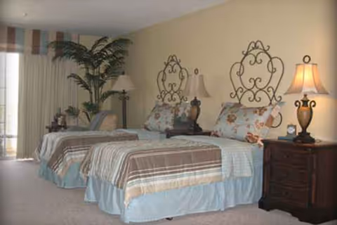 Three twin beds with matching striped bedding and decorative headboards in a bedroom.