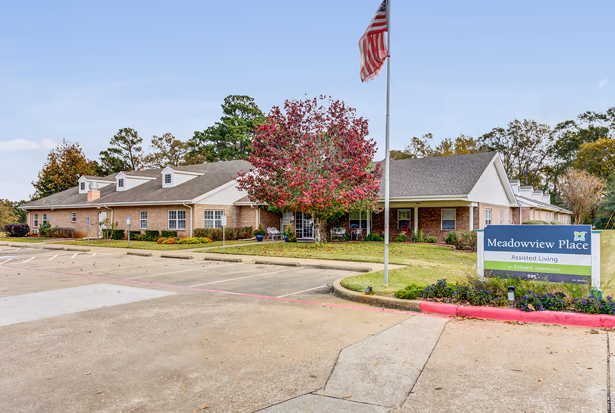 Front view of Meadowview Place assisted living building with a parking lot, an American flag, and a sign.