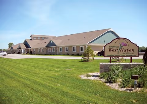 Single-story senior living facility with manicured lawn and a large sign.