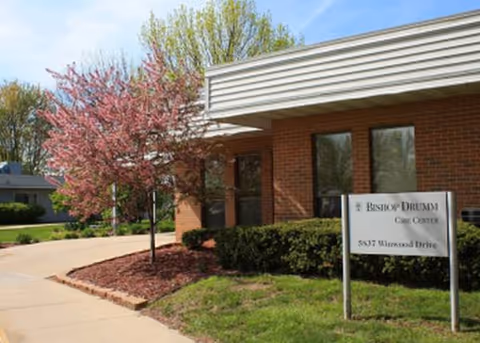 Exterior view of Bishop Drumm Retirement Center with a flowering tree and brick facade.