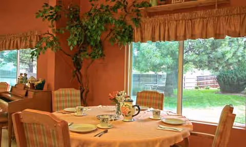 Round dining table set with dishes and teapot near a large window.