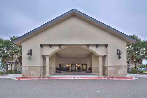 Front view of Windsor Atrium facility with arched entrance, lamps, and palm trees.