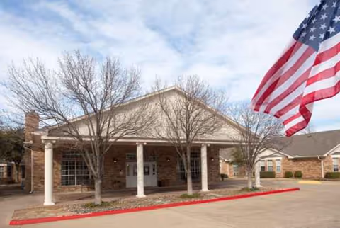 Exterior front of Cariad at Village Creek with brick building, columns, and American flag