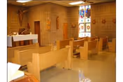 Interior chapel in a Notre Dame Health and Rehabilitation Center with wooden pews and stained glass.